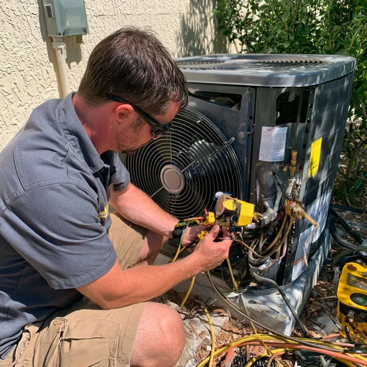 Technician checking the service connections on an outdoor cooling unit
